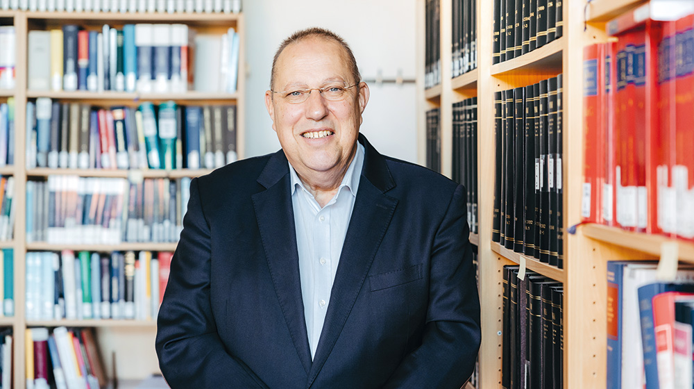 Portrait of Prof. Burgard in front of two bookshelves in his office (Photo: Jana Dünnhaupt / University of Magdeburg)