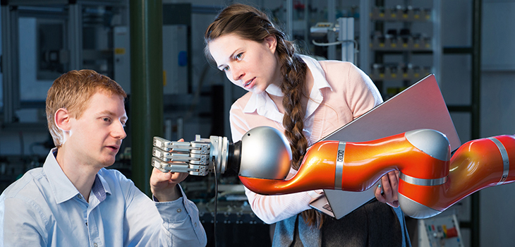 Zwei Forschende arbeiten an einem Kuka-Roboterarm (Foto: Stefan Berger / Uni Magdeburg)