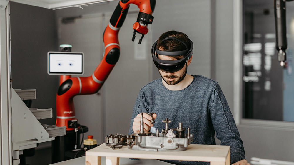 /unimagdeburg_media/Presse/Bilder/Pressemitteilungen/2024/Ein+Mann+mit+VR+Brille+schraubt+an+etwas_+im+Hintergrund+ein+Robotergreifarm+%28c%29+Jana+D%C3%BCnnhaupt+Uni+Magdeburg-height-560-width-1000-p-113138.jpg
