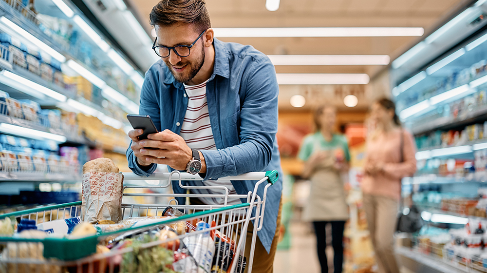 /unimagdeburg_media/Presse/Bilder/Pressemitteilungen/2024/Ein+Mann+steht+im+Supermarkt+mit+Einkaufswagen+und+schaut+auf+sein+Handy+%28c%29+Drazen+Zigic_Shutterstock-height-560-width-1000.jpg